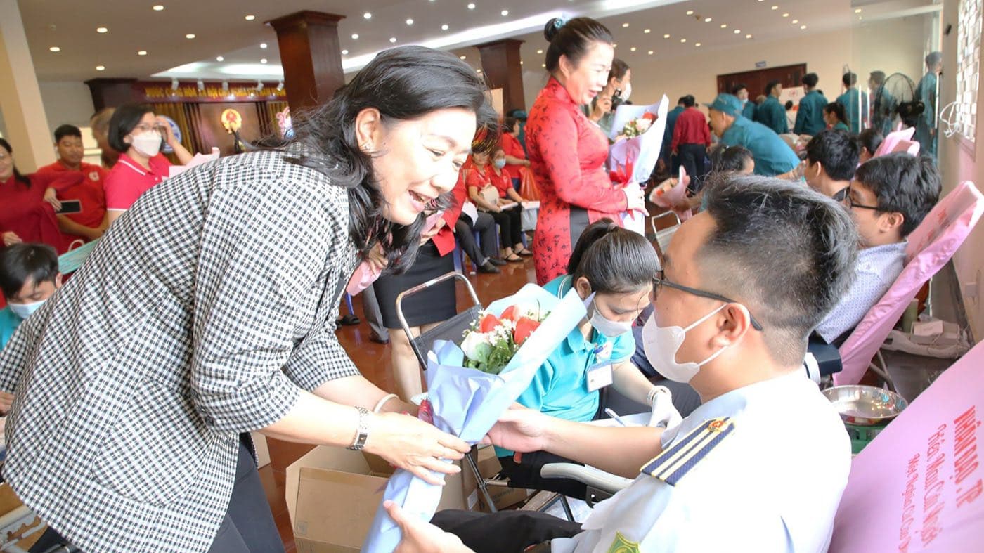 Đại diện ban tổ chức tặng hoa cho một người hiến máu đang ngồi trên ghế hiến